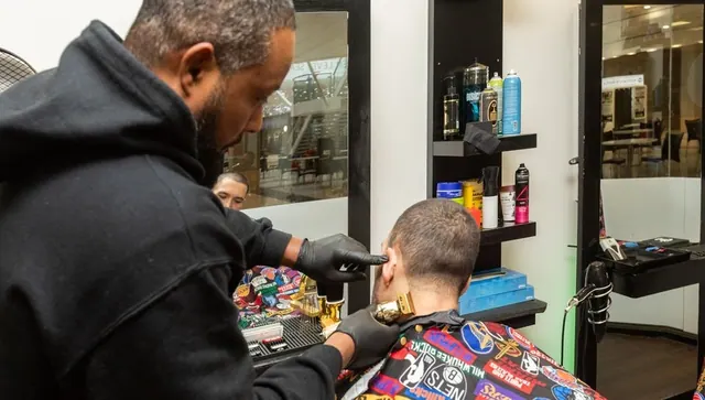 A barber finishing a neckline with gold clippers